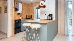 Una cocina moderna con una isla central, taburetes de bar y una lámpara colgante.