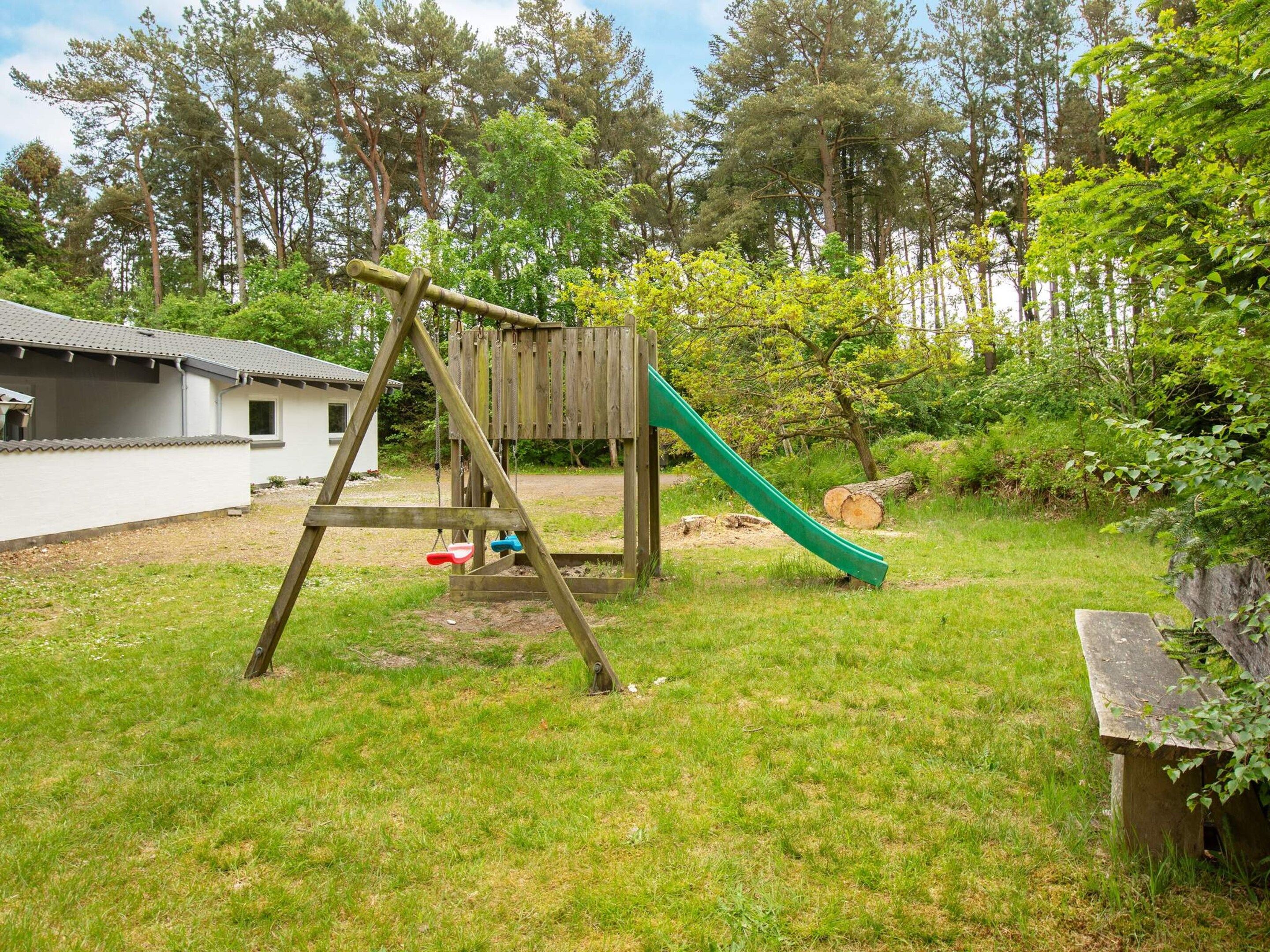 Un ensemble de jeux d’extérieur en bois, comprenant une balançoire et un toboggan, installé dans une cour arrière verdoyante.