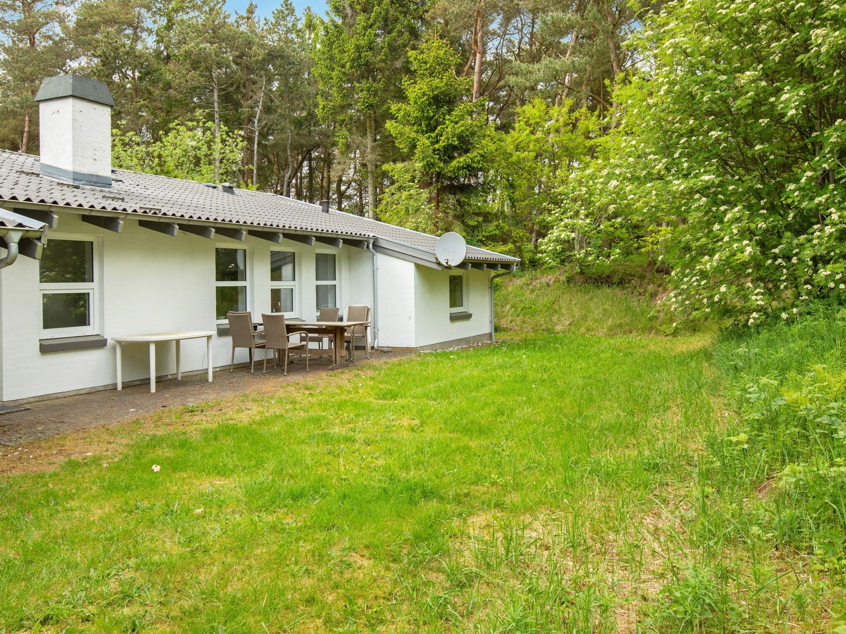 A single-story building with a covered patio area, a dining table with chairs, and a satellite dish.