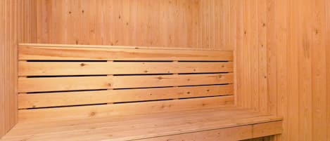 Un banco de madera con listones horizontales, ubicado frente a una pared de madera con tablones verticales.