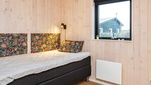 A room with a bed, wooden walls, a window, and a radiator.
