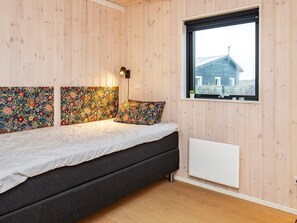 A room with a bed, wooden walls, a window, and a radiator.