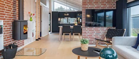 Ein modernes Wohnzimmer mit Kamin, Essbereich und Küche.