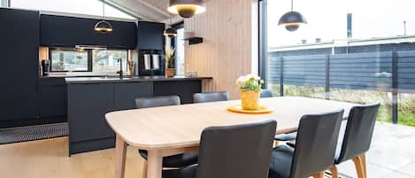 A modern kitchen with dark cabinetry, a wooden dining table, and black chairs.