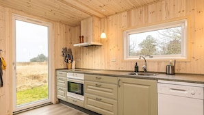 A modern kitchen with wooden walls, a large window, and a view of the outdoors. - Tranquil Nature Escape-by Traum (Thyholm)