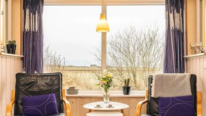 Two leather chairs with purple cushions, a small round table with a vase of flowers, and a lamp. - Tranquil Nature Escape-by Traum (Thyholm)