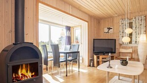 A cozy living room with a wood-burning stove, a dining area, and a TV. - Tranquil Nature Escape-by Traum (Thyholm)