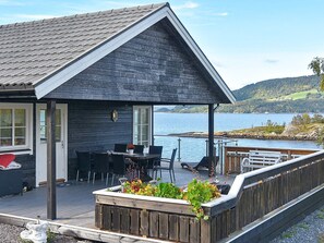 A wooden house with a covered deck overlooking a lake. - 4 Star Holiday Home in Torvikbukt (Gjemnes)
