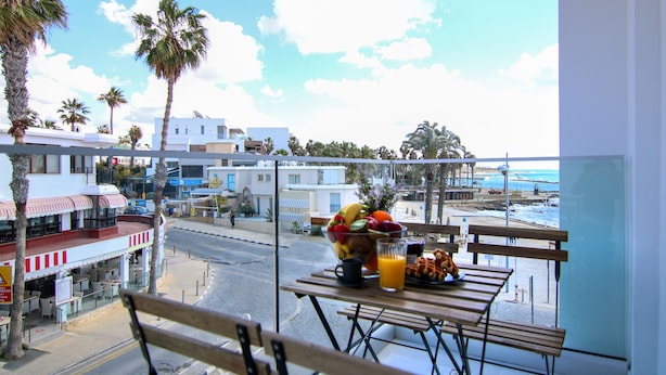 Varanda com mesa posta para o café da manhã, com vista para a praia e edifícios.
