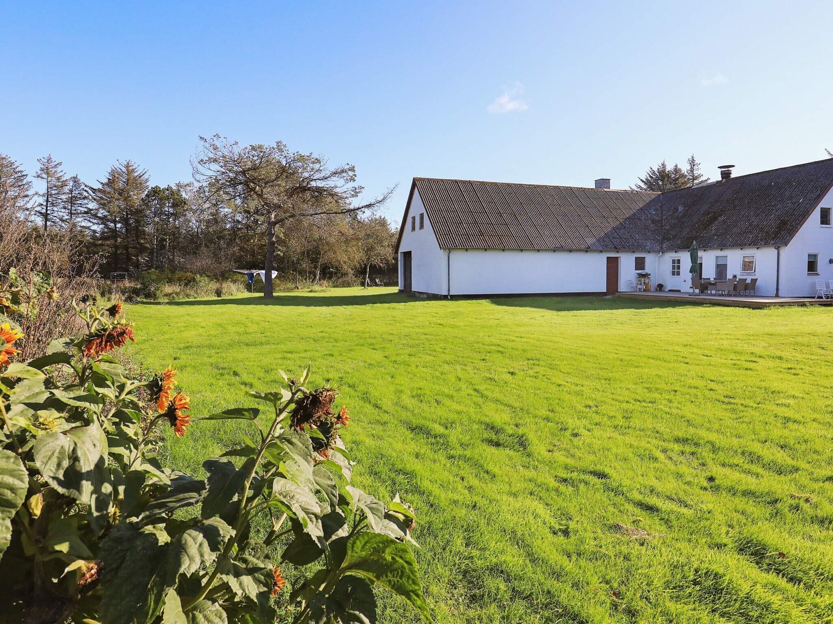A white building with a sloped roof, surrounded by a well-maintained lawn and trees.