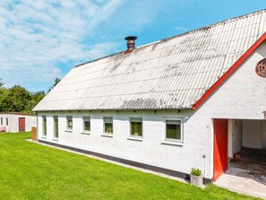 A white building with a corrugated metal roof and a red door.