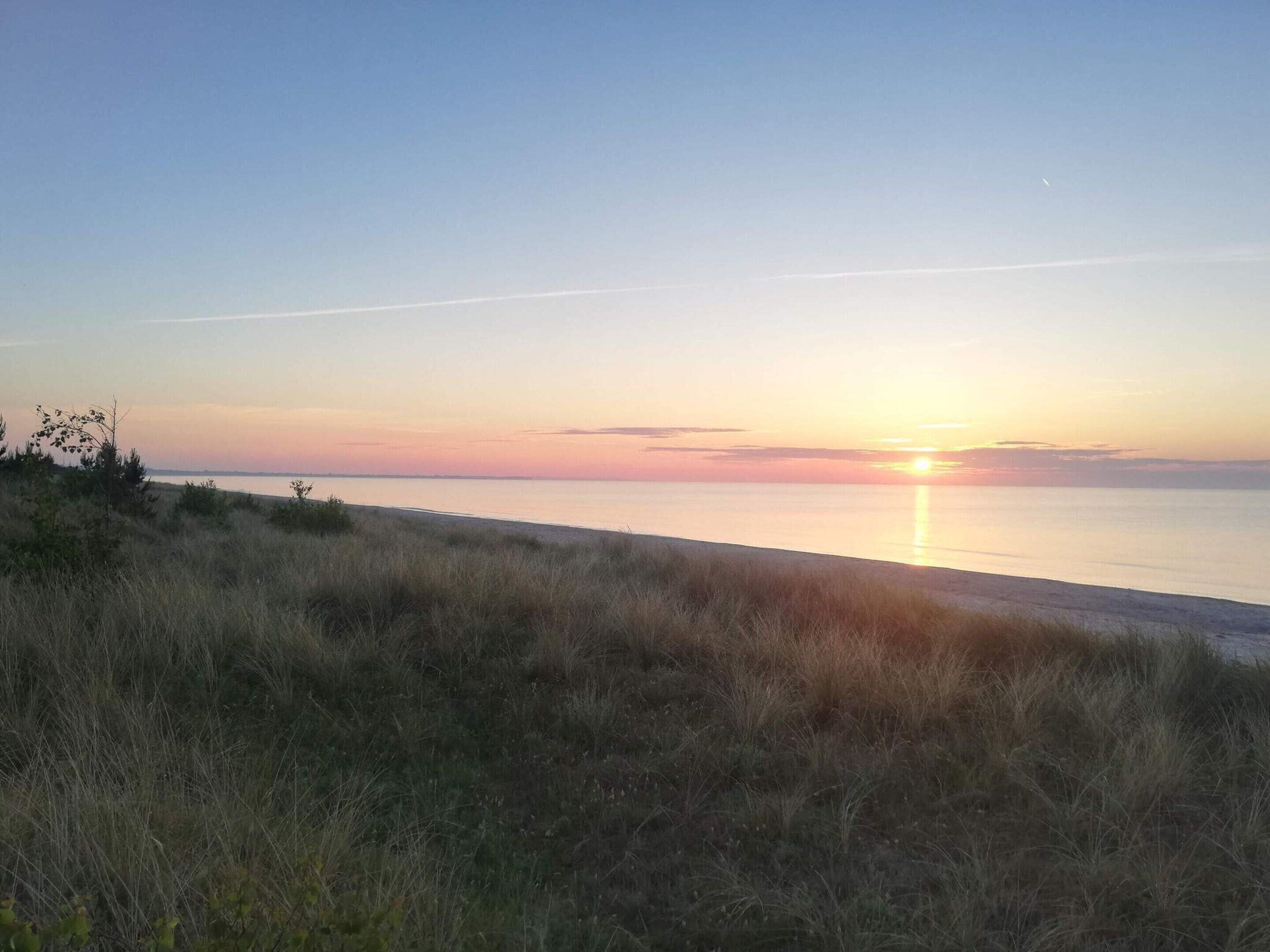 Une plage avec un coucher de soleil sur l’eau.