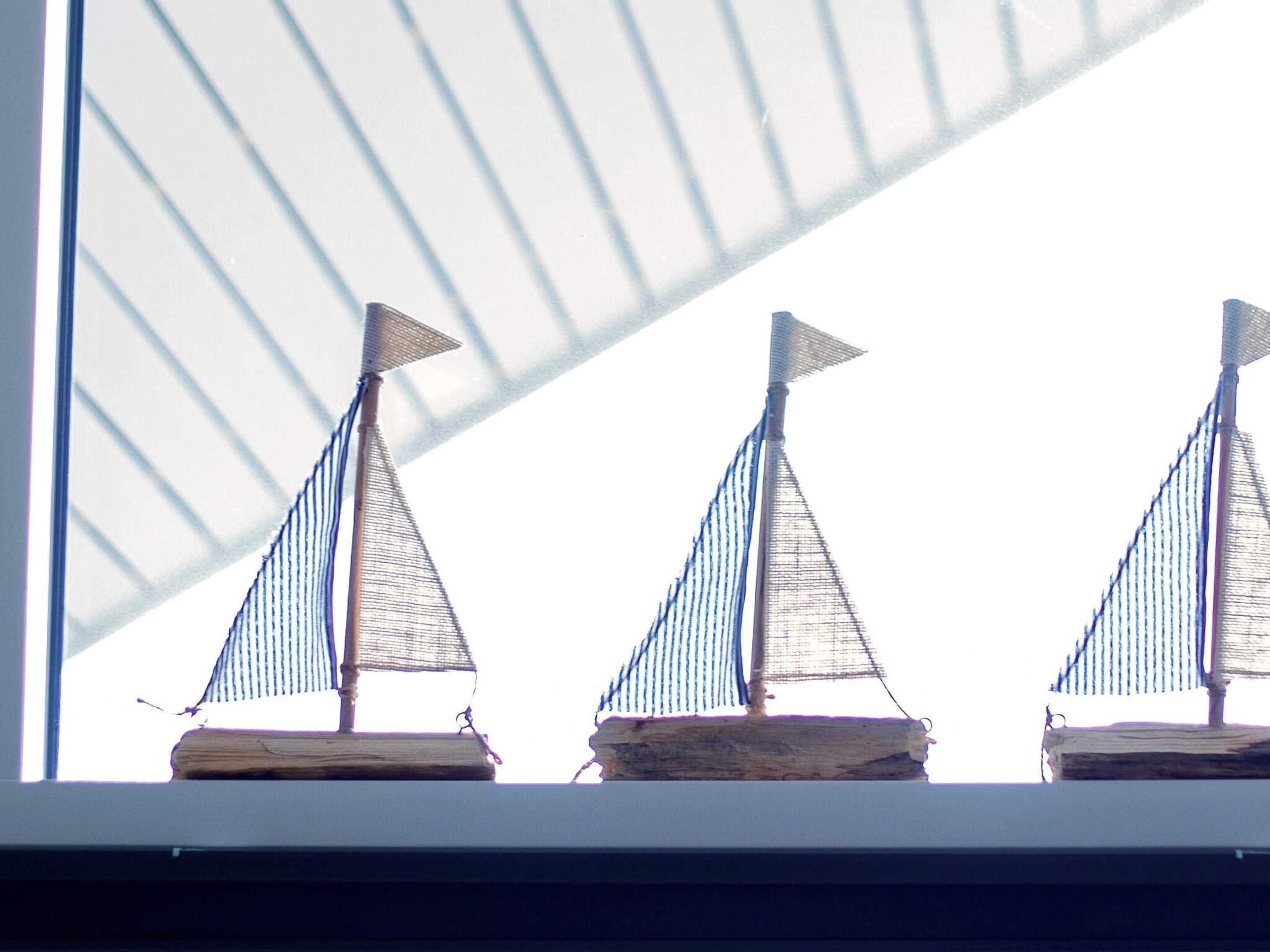 Three model sailboats on a shelf.
