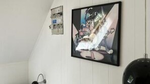 Une pièce avec une œuvre d’art encadrée accrochée au mur, un objet sphérique noir et un mur blanc.