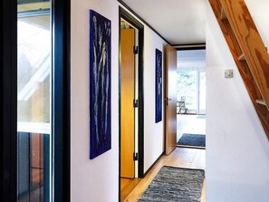 A hallway with a wooden staircase, a door leading to an outdoor area, and a rug on the floor. - Holiday Home in NykÃ¸bing Sj (Nykobing Sjaelland)