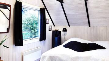 Un dormitorio con una cama, una ventana con cortinas, un radiador y un techo de madera.