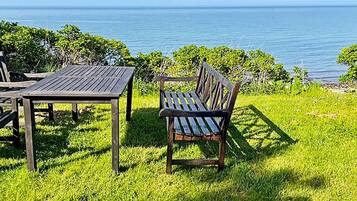 Un espacio al aire libre con una mesa y un banco, con vistas a un cuerpo de agua.