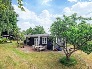 A small, dark-colored house with a porch and a table and chairs. - 6 Person Holiday Home in Jaegerspris (Jægerspris)