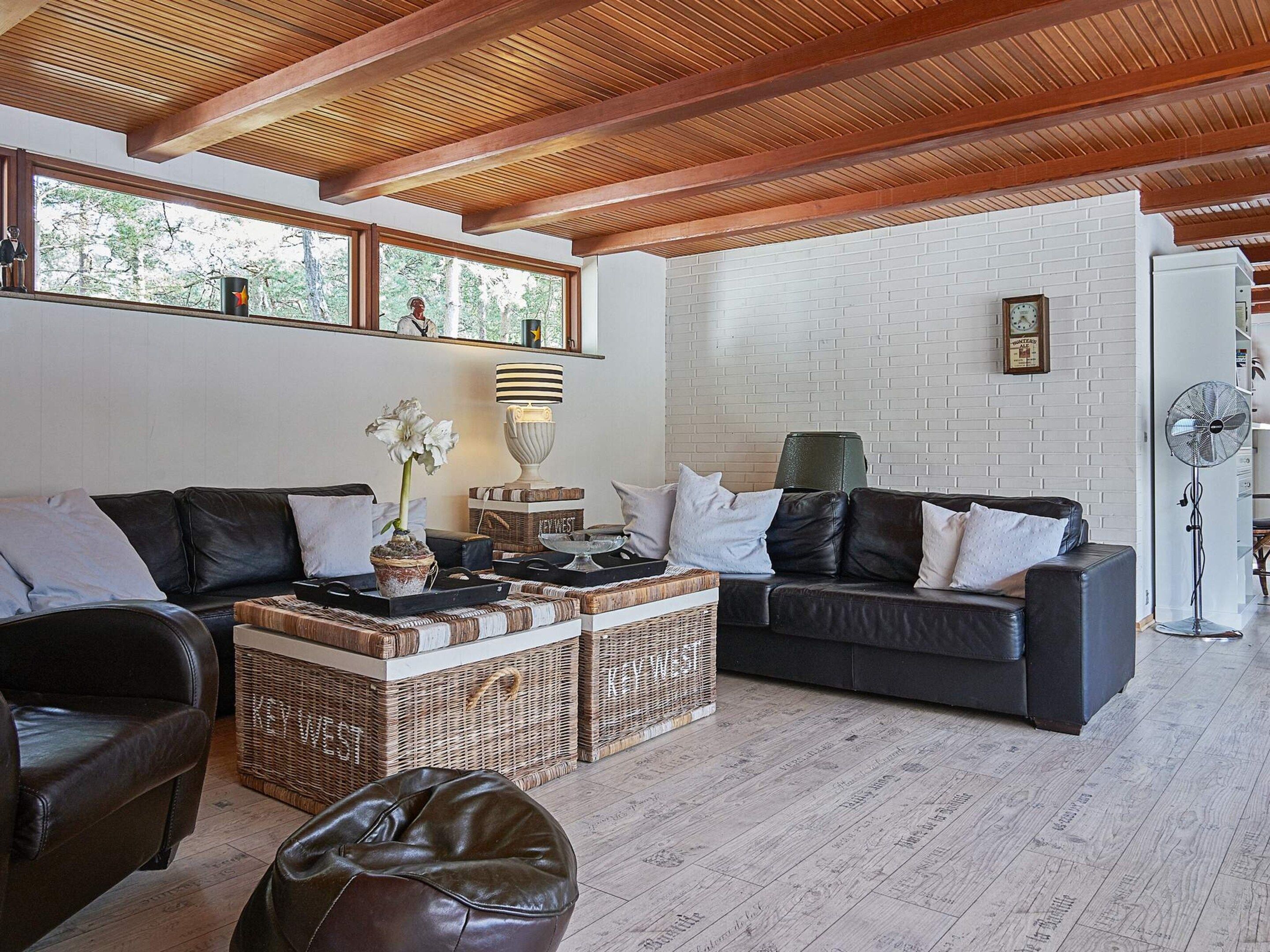 Ein modernes Wohnzimmer mit Holzboden, Ledersofas, einem Couchtisch und einer Wand aus weißen Ziegeln.