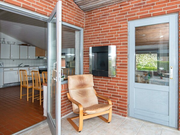 A kitchen with white cabinets, a dining area with wooden chairs, and a sliding glass door leading to an outdoor area. - 6 Person Holiday Home in Hejls (Hejls)