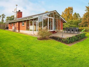A modern house with a glass conservatory, a brick exterior, and a well-maintained lawn.