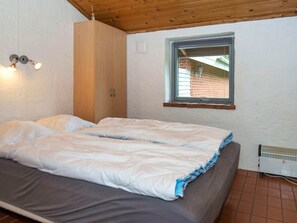A bedroom with a bed, a wooden wardrobe, a window, and a radiator. - 6 Person Holiday Home in Hejls (Hejls)