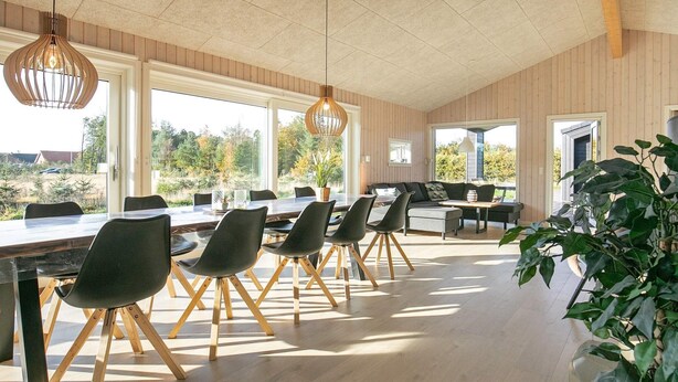 A spacious room with a long table and chairs, large windows, and a view of the outdoors. - Holiday Home in Sæby (Sæby)