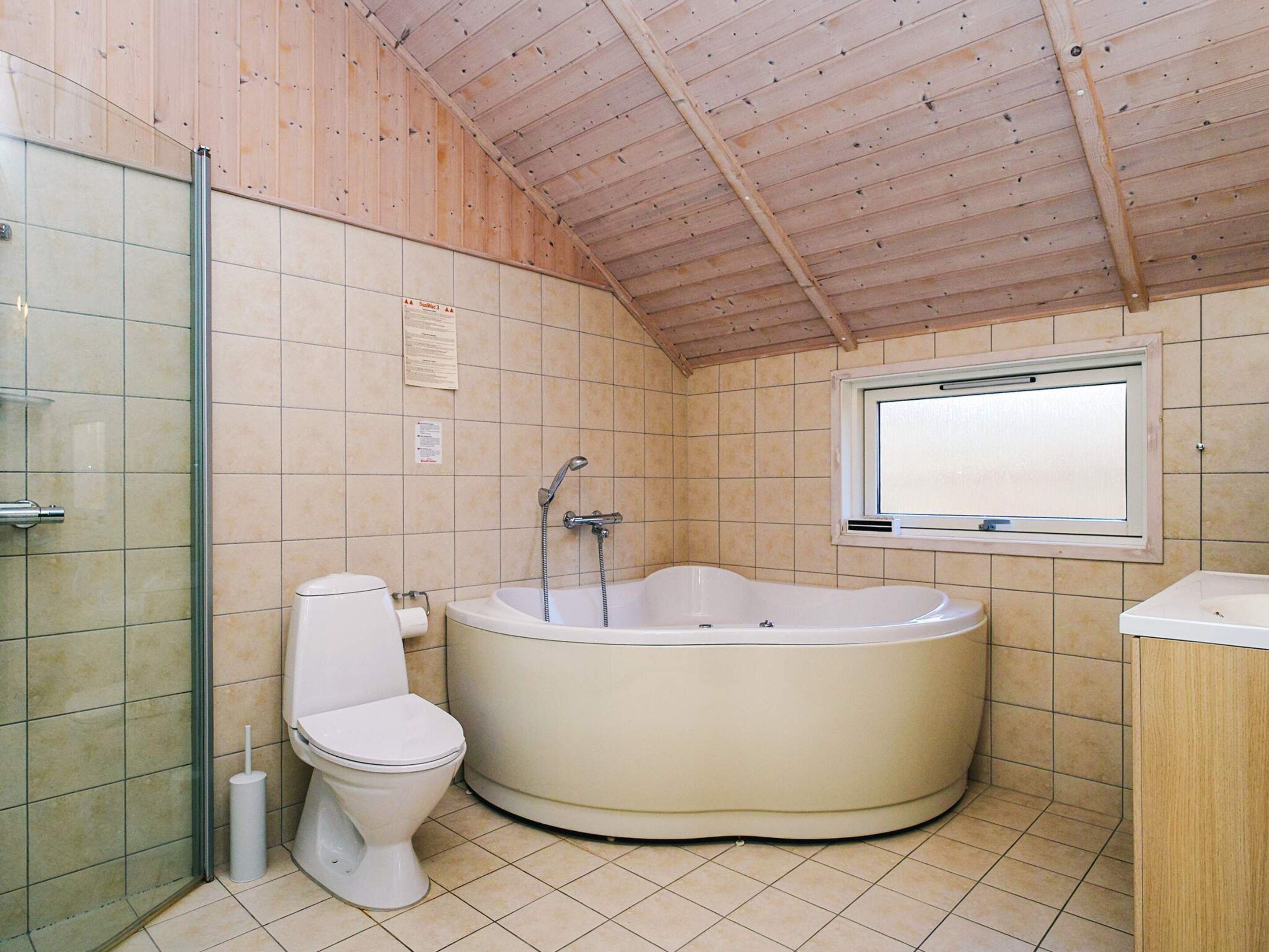 Un baño con bañera, inodoro y ventana.