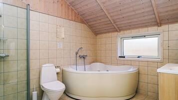Un baño con bañera, inodoro y ventana.