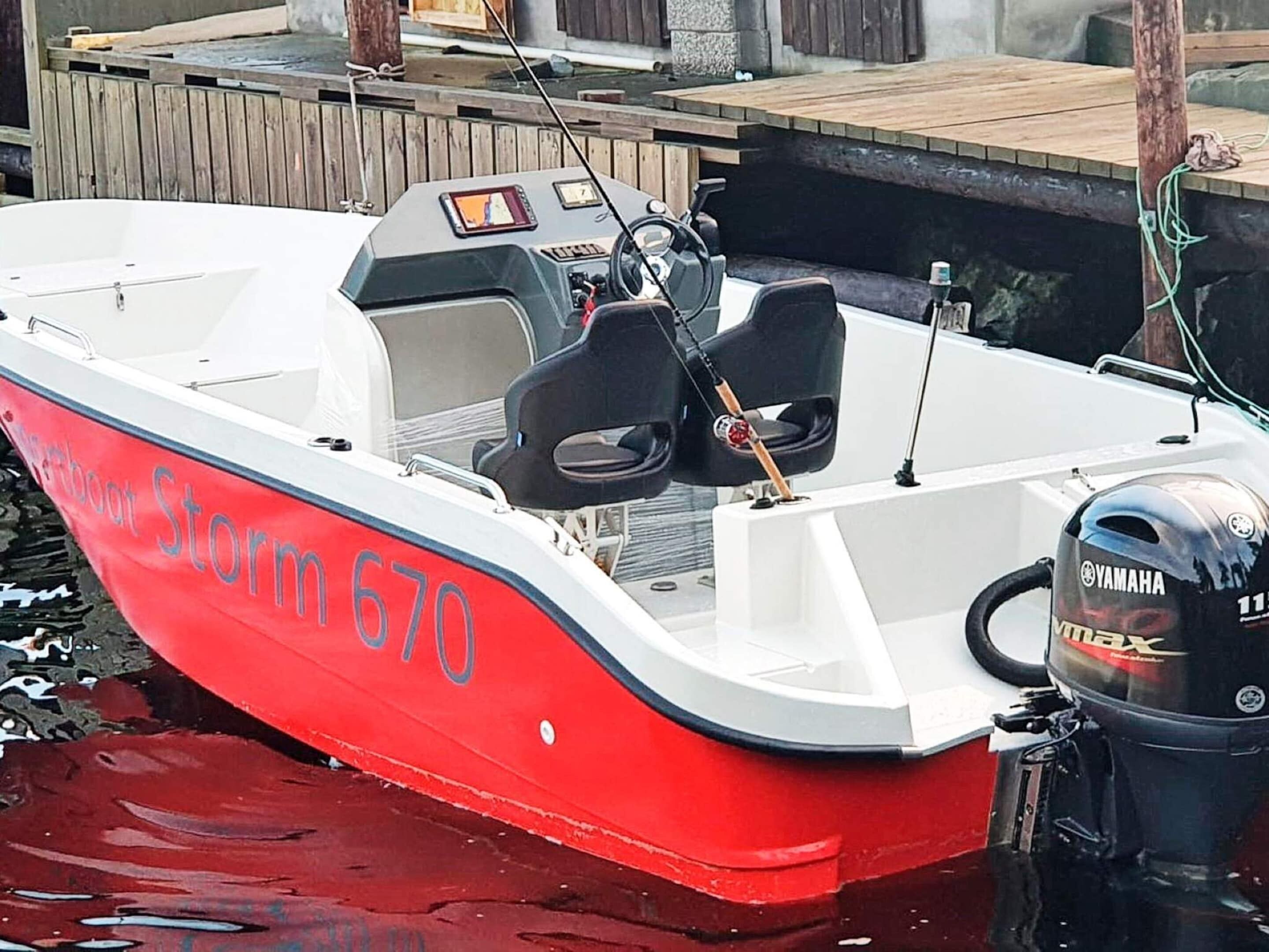 A red and white boat named Storm 670 docked at a wooden pier.