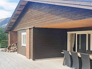 A covered outdoor area with a table and chairs, a brick wall, and a window. - Holiday Home in Svelgen (Bremanger)