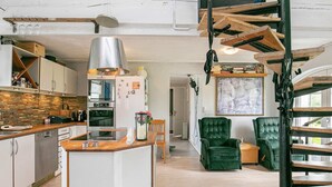A modern kitchen with a central island, wooden flooring, and a staircase with a unique design. - 6 Person Holiday Home in Lokken (Lokken)