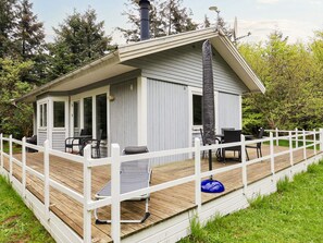 A small cabin with a deck, outdoor seating, and a chimney.