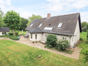 A two-story house with a sloped roof, a patio with outdoor furniture, and a garden. - 8 Person Holiday Home in Fur (Fur)