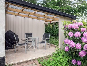 An outdoor patio with a covered seating area, a grill, and a flowering shrub. - 8 Person Holiday Home in Fur (Fur)