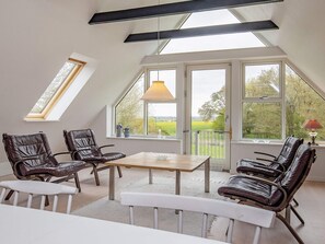 A room with a sloped ceiling, large windows, and a table with chairs. - 8 Person Holiday Home in Fur (Fur)