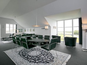 A modern conference room with a large table, green chairs, and a patterned rug.