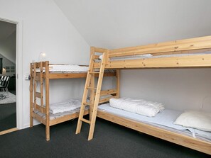 Dormitorio con literas, una escalera de madera, escritorio y silla.