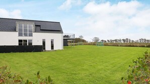 Une maison moderne avec une grande pelouse et deux buts de football.