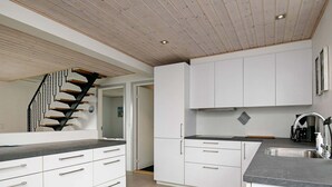 Une cuisine moderne avec des meubles blancs, un plan de travail noir et un escalier en bois.