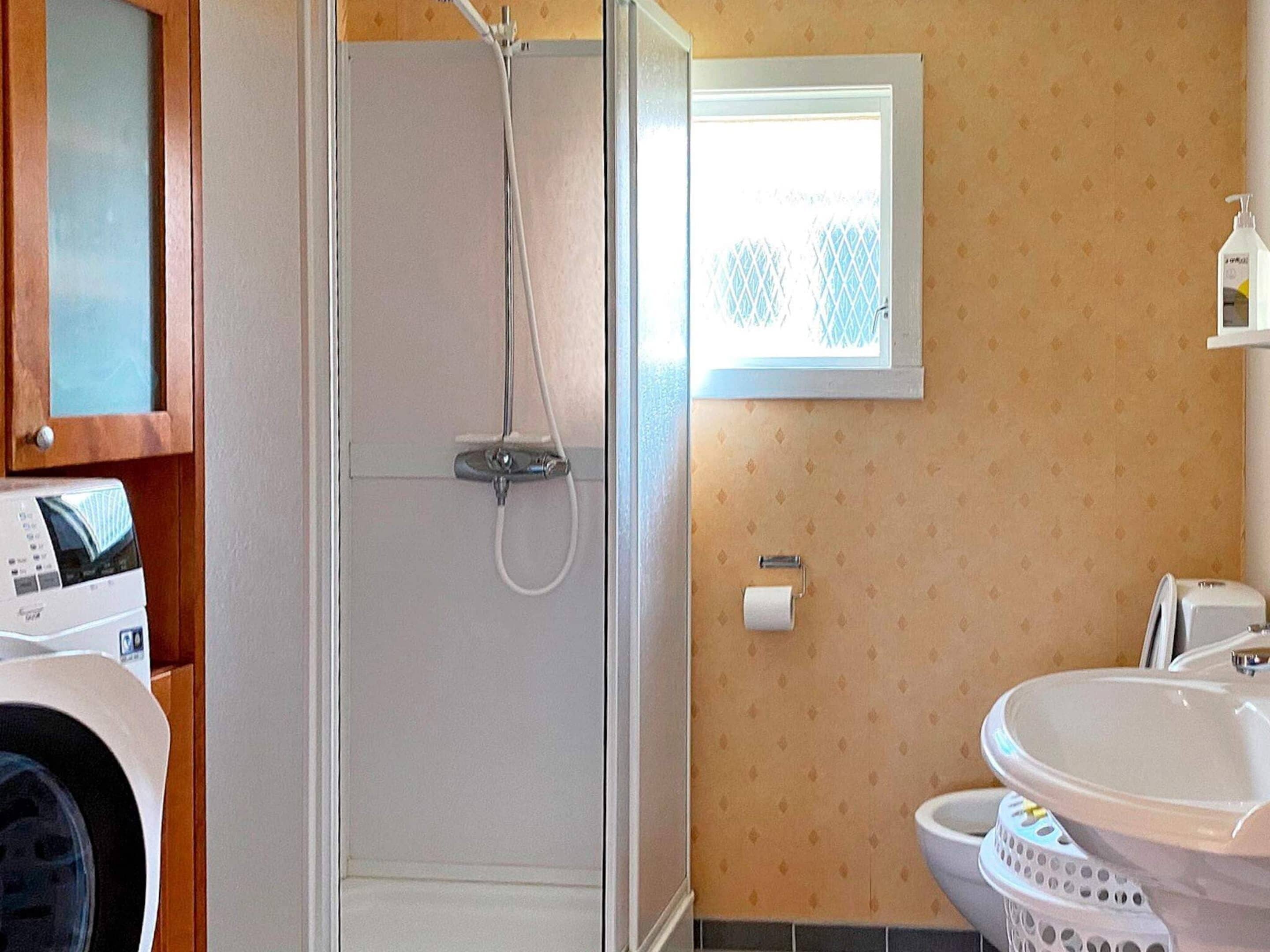 Ein Badezimmer mit Dusche, Toilette, Waschbecken und einem Fenster.