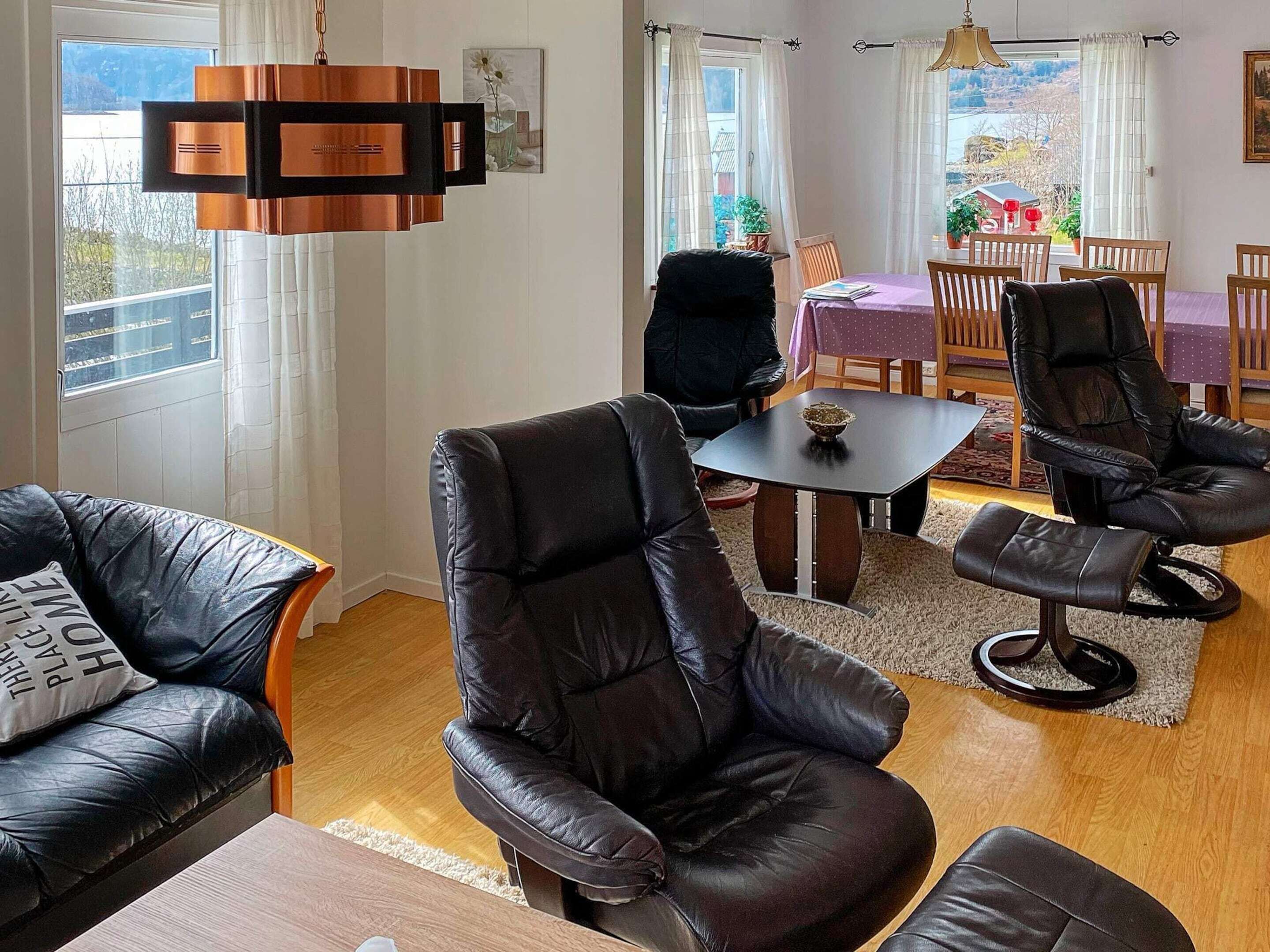 A modern living room with leather sofas, a dining table, and a view of the outdoors.
