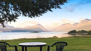 A table and two chairs in a grassy area with a lake and mountains in the background. - 6 Person Holiday Home in Storsteinnes (Balsfjord)