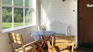 A cozy room with a wooden bench, a small table with a blue tablecloth, and a view of a forest through large windows. - 6 Person Holiday Home in Storsteinnes (Balsfjord)