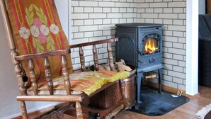 A corner room with a brick wall, a wooden rocking chair, a small stove, and a fireplace. - 6 Person Holiday Home in Storsteinnes (Balsfjord)