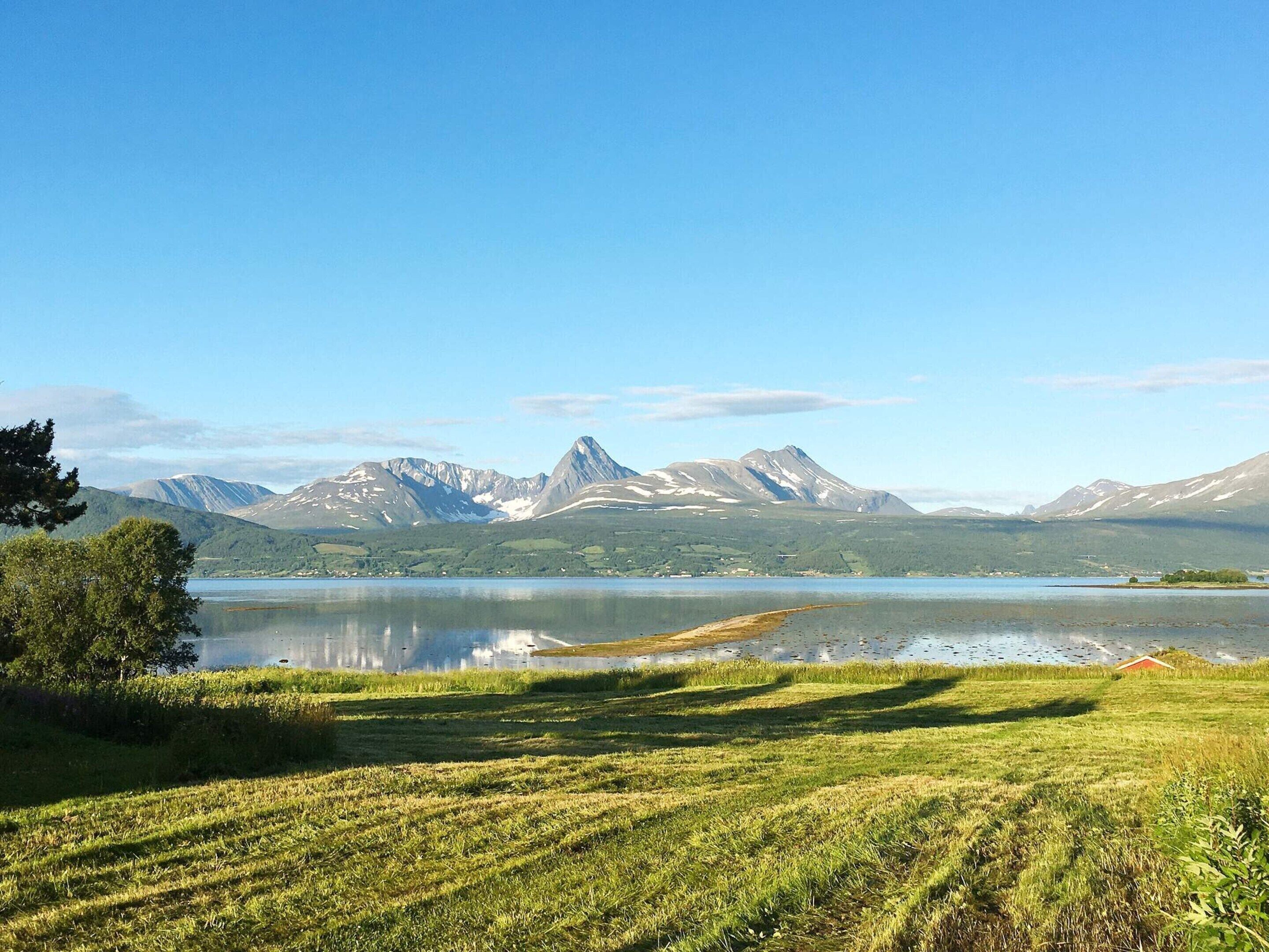 A mountainous landscape with a lake and grassy fields.