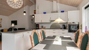 Una cocina moderna con armarios blancos, una isla central e iluminación colgante.
