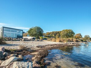 Et moderne hus ved en flod med frit udsyn til vandet og de omkringliggende træer.