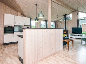 A modern kitchen with wooden cabinets, a built-in oven, and pendant lighting.