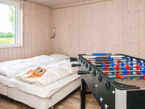 Una habitación con cama, mesa de fútbol de mesa y ventana con vistas al verdor.